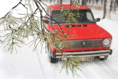 Chernihiv, Ukraine - January 20, 2020: Old red VAZ 21011 car in the winter forest. Foreground branches clipart