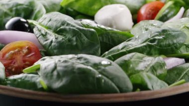 Çeri domates ve mozzarella taze salatanın içine düşüp zıplıyorlar. Yeşil yapraklar, ıspanak, siyah zeytin, soğan. Ağır çekim. Tam HD 240 fps