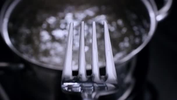 Fourchette descend dans la casserole avec de l'eau bouillante chaude. Coup 4K .