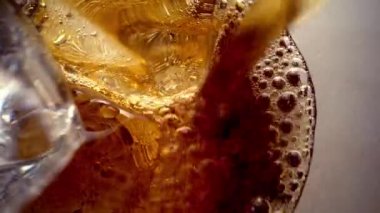 Laowa 24 mm sonda merceği kola bardağına dalıyor. Kabarcıklarla kaplı buz küpleri. Cama kola dökülüyor. Lezzetli bir içecek. Coca-Cola ile dolu bardağın içine bak. 4K