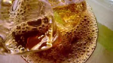 Laowa 24 mm sonda merceği kola bardağına dalıyor. Kabarcıklarla kaplı buz küpleri. Cama kola dökülüyor. Lezzetli bir içecek. Coca-Cola ile dolu bardağın içine bak. 4K