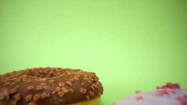 Laowa 24 mm sonda merceği güzel renkli donuttan geçiyor. Lezzetli çörekler kapanıyor. Tatlı tatlı. Serpme. Yeşil arka plan. Çöreğin içinde. 4K