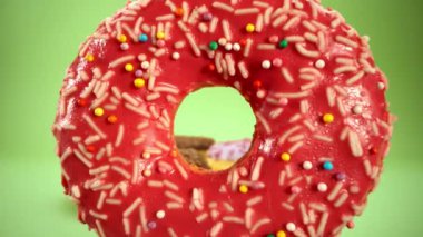 Laowa 24 mm sonda merceği güzel renkli donuttan geçiyor. Lezzetli çörekler kapanıyor. Tatlı tatlı. Serpme. Yeşil arka plan. Çöreğin içinde. 4K