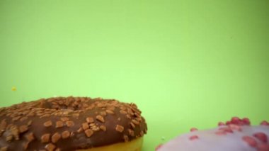 Laowa 24 mm sonda merceği güzel renkli donuttan geçiyor. Lezzetli çörekler kapanıyor. Tatlı tatlı. Serpme. Yeşil arka plan. Çöreğin içinde. 4K