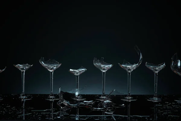 Ezilmiş şarap kadehleri. Kırık cam eşyalar. Cam kıymıkları. Siyah arkaplanda dramatik çekim