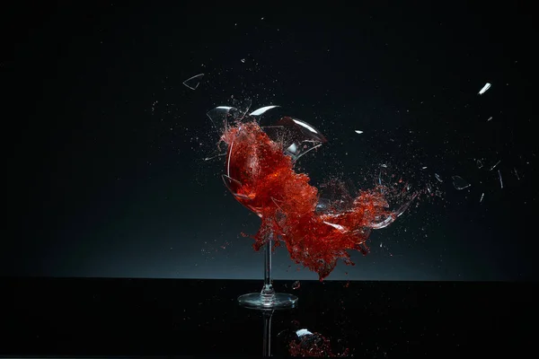 Kırmızı şarap kadehleri uçuyor, çarpışıyor ve siyah arka planda eziliyor. Sıçramalar. Kırık cam. Sıvıların yüksek hız fotoğrafçılığı