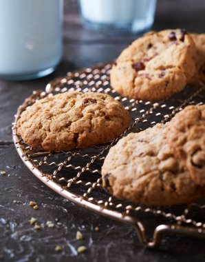 Altın serin bir rafta taze pişmiş kurabiyeler. Bir bardak süt, siyah arka planda süt şişesi.