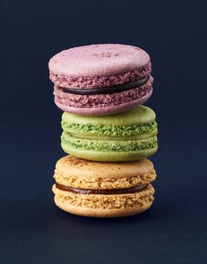 Koyu mavi arka planda üç renkli badem kurabiyesi.      