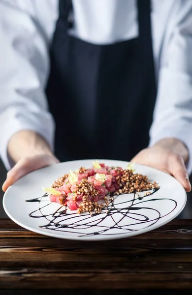 Restoran şefi çok güzel karabuğday ve ton balığı servis ediyor. Siyah beyaz üniforma, ahşap tezgah..