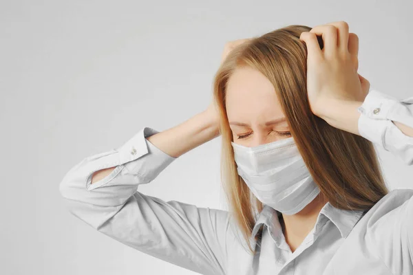医療マスクの若い女性は頭を抱え頭痛に悩まされ — ストック写真