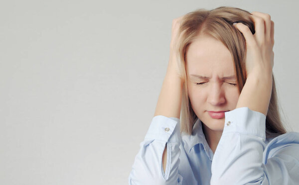 молодая блондинка держит голову. Женщина с головной болью

