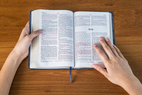 En kvinna läser en bibel på ett träbord — Stockfoto