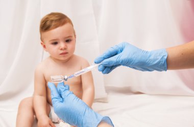 Doktor enjeksiyon ile hasta bebeği aşılamak için şırınga tutar