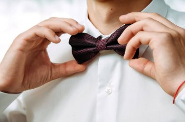 Beyaz yakalı damat papyonunu düzeltiyor.