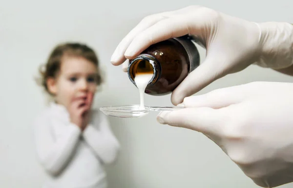 Маленькая больная девочка ждет лекарств, льющихся в ложку — стоковое фото