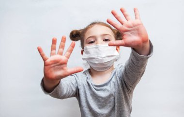 Tek kullanımlık maskeli küçük kız ellerini gösteriyor. Coronavirus salgını koruması
