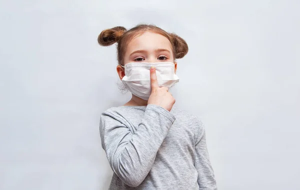 Tek kullanımlık maskeli küçük kız parmağını kaldırdı. Coronavirus salgını koruması