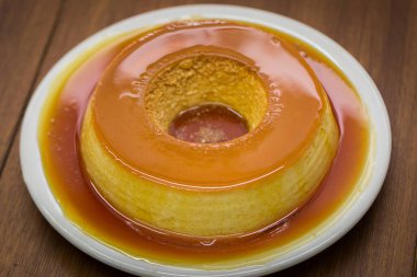 Pudim de leite, sütlü, yumurtalı ve üzerine karamel sosu sürülmüş konsantre sütle lezzetli bir Brezilya turtası. (Vanilyalı puding türü) Tahta masada beyaz tabakta servis edilir..