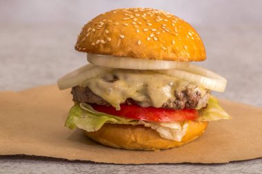 Kahverengi kağıtta salatalı çizburger.