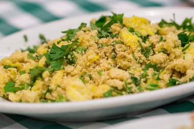 Yumurtalı manioc farofa porsiyonu, tipik Brezilya yemeği yeşil ve beyaz kareli masa örtüsü.