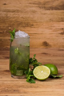 Bir bardak naneli mojito ve ahşap arka planda limon..