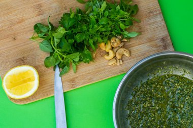 Pesto sosu. Yeşil arkaplanda taze pesto sosu, malzemeler, domates, soğan, fesleğen, ahşap tahtada..