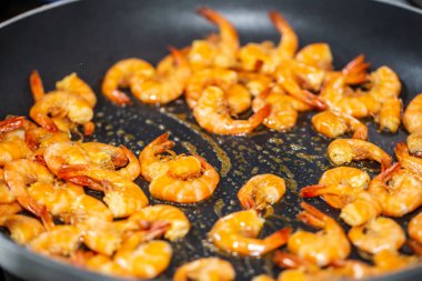 Siyah tavada zeytinyağında sarımsaklı karides kızartma işlemi. Aşama aşama.