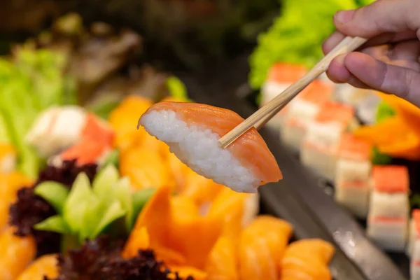 Ruční Držení Lososa Sushi Japonským Jídlem Formou Bufetu Pozadí — Stock fotografie