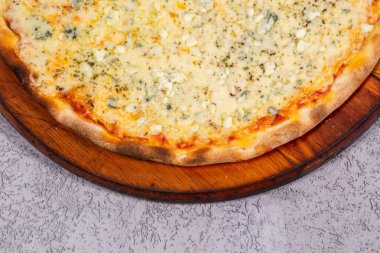 Gri arka planda dört peynirli pizza.