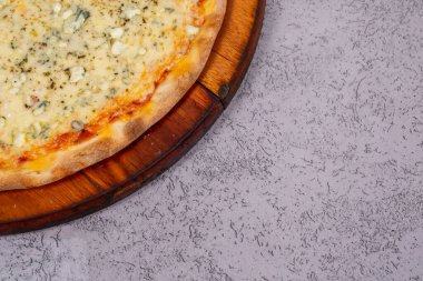 Gri arka planda dört peynirli pizza.