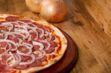 Ahşap arka planda pepperoni pizza. Pizza de calabresa adında Brezilya pizzası..