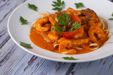Domates soslu makarna ve deniz ürünleri. Kırsal arkaplanda.