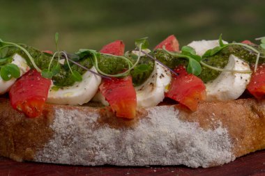  Bufalo mozzarella bruschetta 'yı domates ve pesto ile kaplayın..