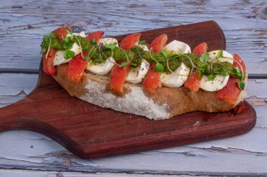 Köy arka planında lezzetli peynir, domates ve pesto bruschetta..