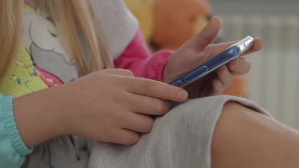 可爱的小女孩在沙发上的智能手机上玩耍 — 图库视频影像
