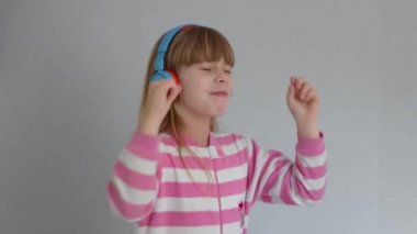 Sevimli küçük kız kablosuz kulaklıkla müzik dinliyor.