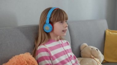 Sevimli küçük kız kablosuz kulaklıkla müzik dinliyor.
