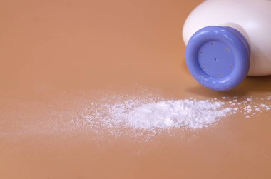 Turuncu arka planda beyaz ince toz vücut pudrası..