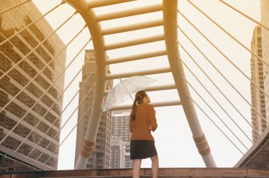 Kırmızı ofis takım elbise şeffaf şemsiye tutan Taylandlı güzel kadın.