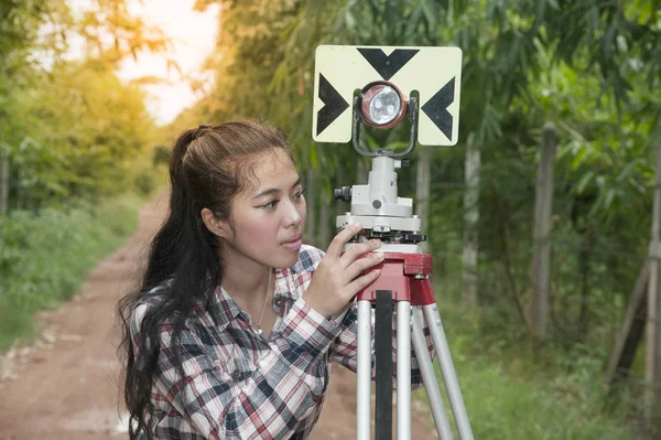 Kvinnliga Surveyor eller ingenjör att göra åtgärden av Prisma reflex på ett fält. — Stockfoto