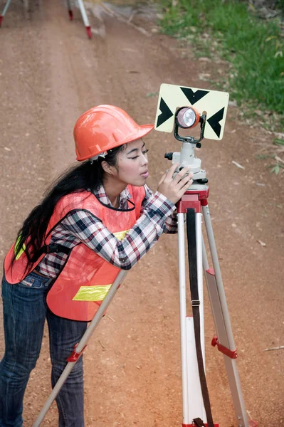 Vrouwelijke Surveyor of ingenieur maatregel door prism reflector op een veld maken. — Stockfoto