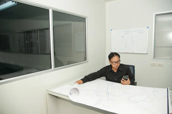 Architect and construction engineer or surveyor discussing plan and map in office room.