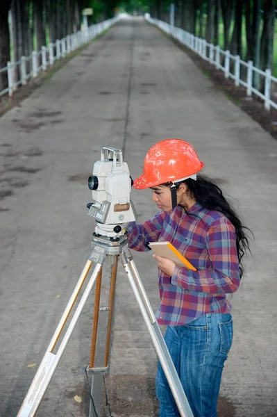 Vrouwelijke Surveyor of ingenieur maatregel op het veld maken. — Stockfoto