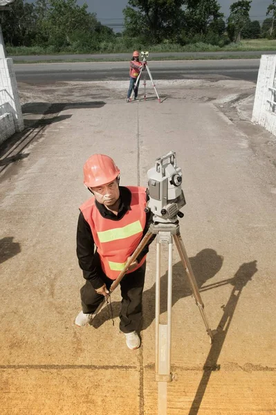 Landmeter of ingenieur maatregel met partner op het veld maken. — Stockfoto