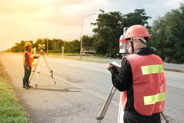 Landmeter of ingenieur maatregel met partner op het veld maken. — Stockfoto