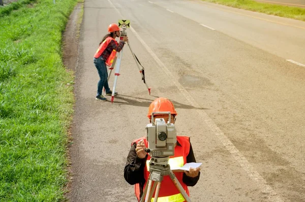 Surveyor ou Engenheiro fazendo medidas com parceiros em campo . — Fotografia de Stock