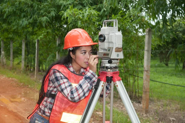 Vrouwelijke Surveyor of ingenieur maatregel door Theodoliet op straat in een veld maken. — Stockfoto