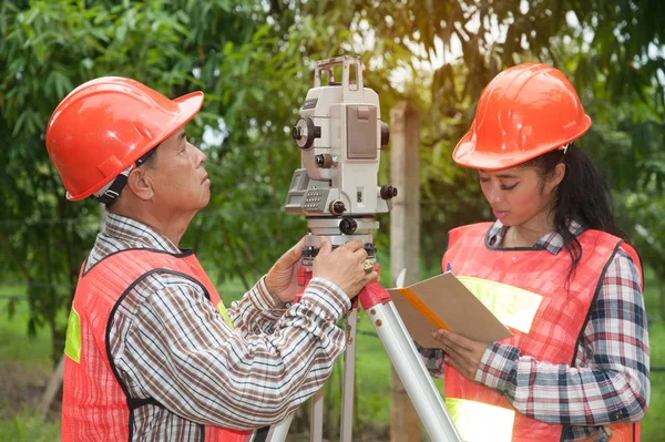 Surveyor eller ingeniør gør foranstaltning af Theodolite med partner på gaden i et felt . - Stock-foto