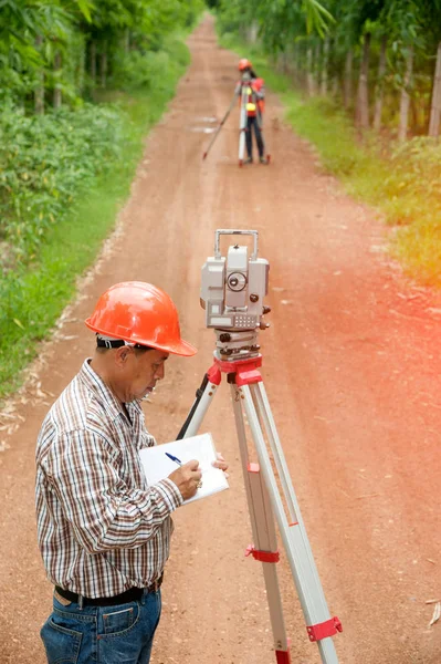 Landmeter of ingenieur maatregel maken door Theodoliet en prisma reflector met partner in een veld. — Stockfoto