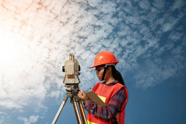 Vrouwelijke Surveyor of ingenieur maatregel door Theodoliet op het veld maken. — Stockfoto